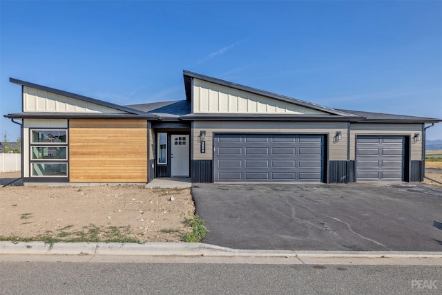 view of front of house featuring aphalt driveway, board and batten siding, and an attached garage