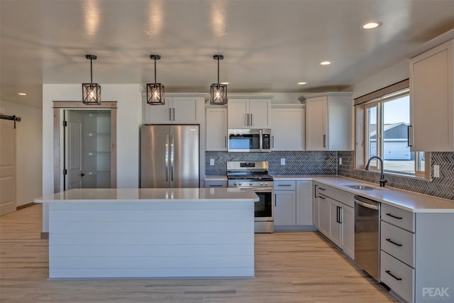 kitchen featuring light countertops, appliances with stainless steel finishes, a kitchen island, and a sink