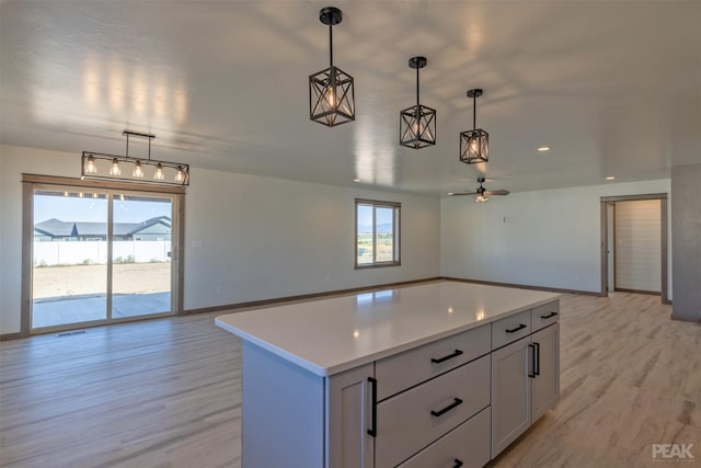 kitchen with open floor plan, a center island, light countertops, light wood-style floors, and pendant lighting