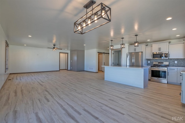 kitchen featuring stainless steel appliances, a center island, open floor plan, and hanging light fixtures