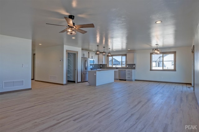 kitchen featuring a center island, decorative light fixtures, visible vents, appliances with stainless steel finishes, and open floor plan