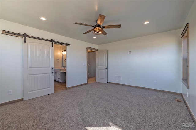 unfurnished bedroom with carpet, recessed lighting, visible vents, a barn door, and baseboards