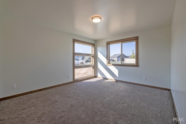 carpeted empty room featuring baseboards