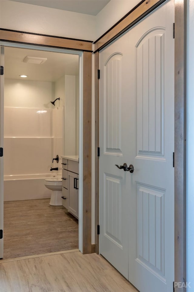 bathroom featuring shower / washtub combination, wood finished floors, and toilet