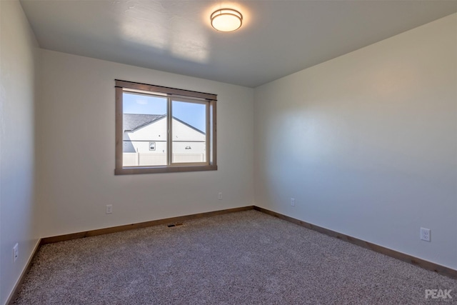 spare room with baseboards and carpet flooring