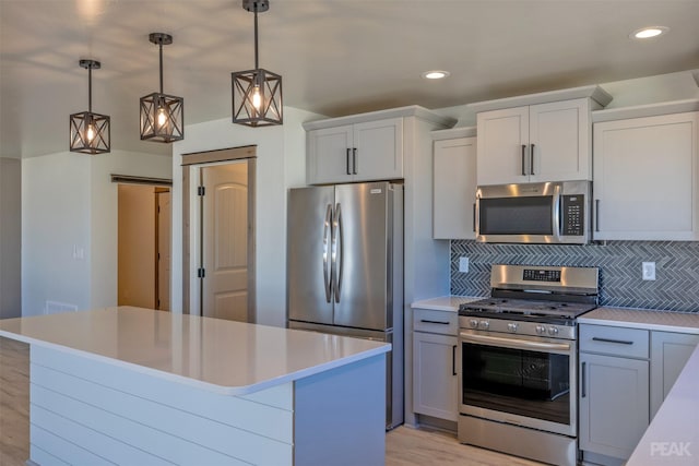 kitchen featuring decorative light fixtures, stainless steel appliances, light countertops, a barn door, and a kitchen island