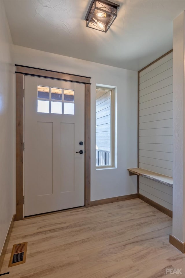 foyer entrance with light wood-style flooring, visible vents, and baseboards