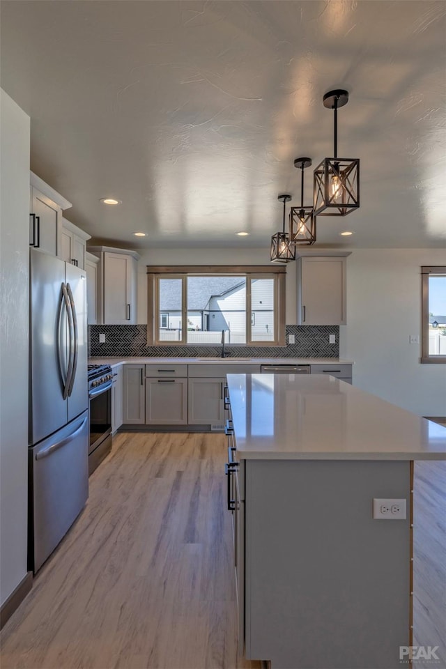 kitchen featuring stainless steel appliances, a kitchen island, plenty of natural light, and light countertops