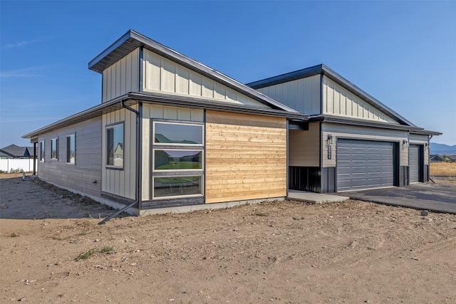 view of home's exterior with board and batten siding, driveway, and an attached garage