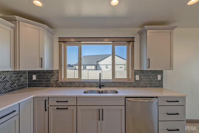 kitchen featuring recessed lighting, light countertops, decorative backsplash, stainless steel dishwasher, and a sink