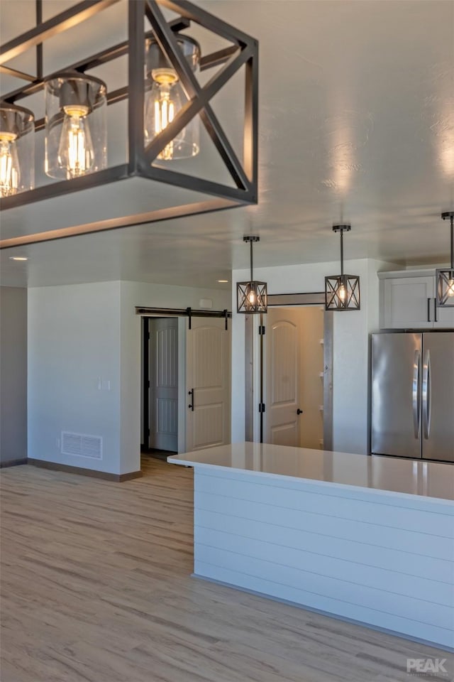 kitchen featuring hanging light fixtures, a barn door, visible vents, and freestanding refrigerator