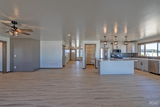 kitchen with pendant lighting, light countertops, appliances with stainless steel finishes, open floor plan, and a kitchen island