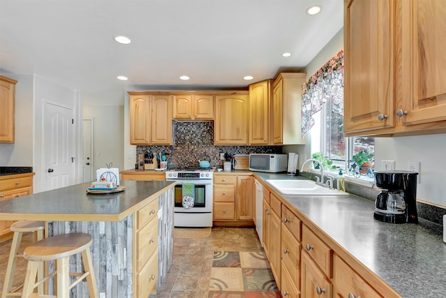 kitchen featuring recessed lighting, white appliances, a sink, a kitchen breakfast bar, and backsplash