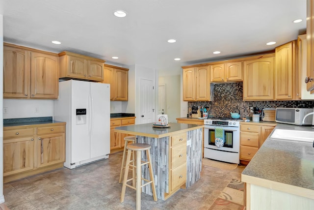 kitchen with white appliances, a breakfast bar area, a kitchen island, and recessed lighting