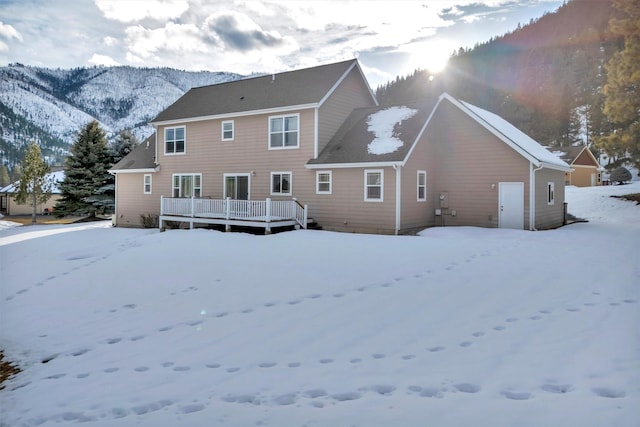 snow covered property with a deck with mountain view