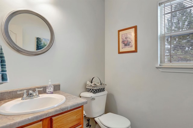 half bathroom featuring plenty of natural light, vanity, and toilet