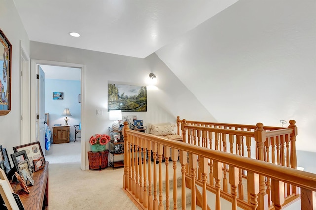 corridor featuring light carpet, vaulted ceiling, and an upstairs landing