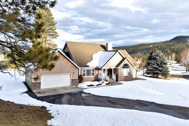 view of front of property with a garage, a chimney, aphalt driveway, a mountain view, and brick siding