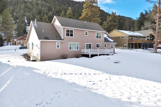 snow covered house featuring a wooden deck