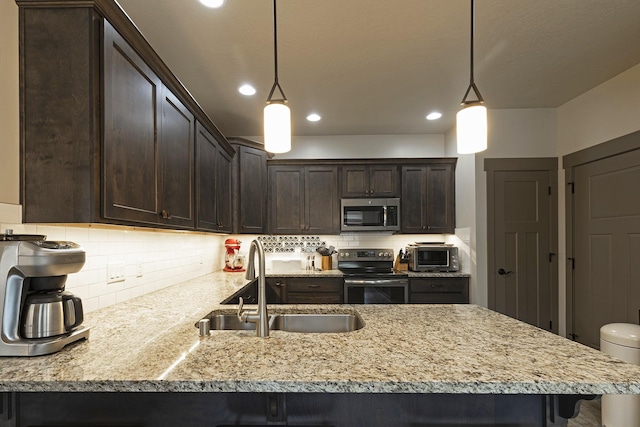 kitchen featuring stainless steel appliances, decorative light fixtures, a sink, and dark brown cabinetry