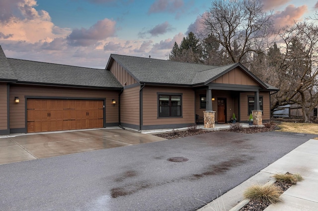 view of front of property featuring driveway, a shingled roof, a garage, and board and batten siding