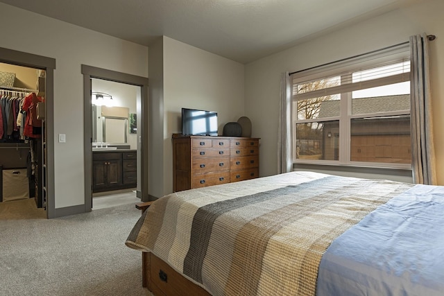 bedroom featuring light carpet, baseboards, ensuite bath, a spacious closet, and a closet