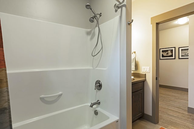 bathroom with baseboards, shower / bathing tub combination, wood finished floors, and vanity