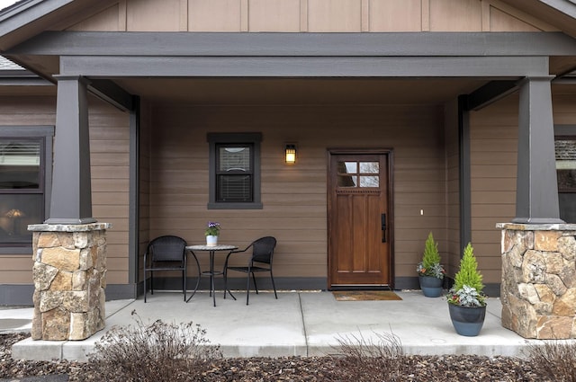 view of exterior entry with a porch and board and batten siding