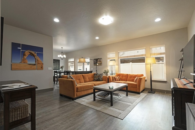 living room featuring recessed lighting, a notable chandelier, baseboards, and wood finished floors