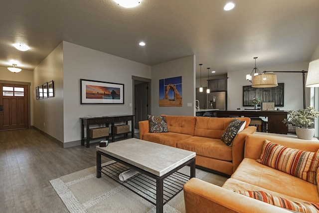 living area with baseboards, wood finished floors, and recessed lighting