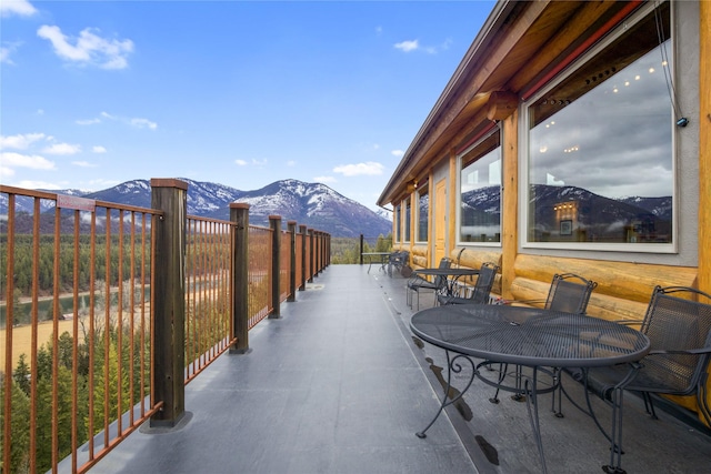 view of patio with outdoor dining area, a mountain view, and a balcony