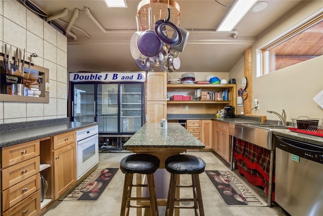 kitchen featuring dark countertops, a breakfast bar area, oven, open shelves, and stainless steel dishwasher