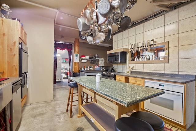 kitchen featuring dark countertops, a kitchen island, appliances with stainless steel finishes, and a breakfast bar area