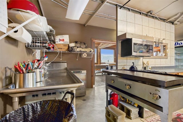 kitchen with concrete flooring, butcher block counters, and stainless steel microwave