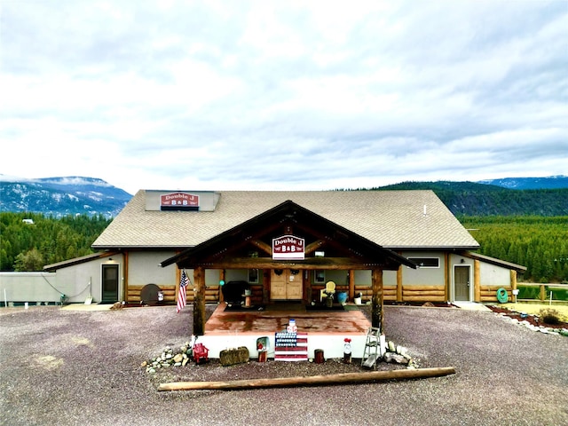 view of front of home featuring driveway, a shingled roof, a mountain view, and stucco siding