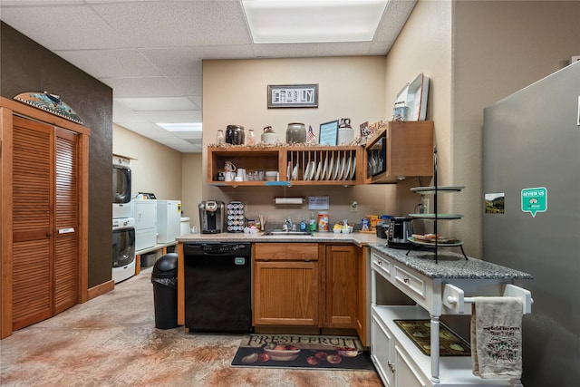 kitchen with brown cabinets, stacked washer / dryer, freestanding refrigerator, a drop ceiling, and dishwasher