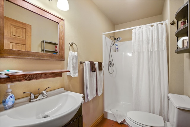 bathroom with a sink, a shower stall, toilet, and tile patterned floors