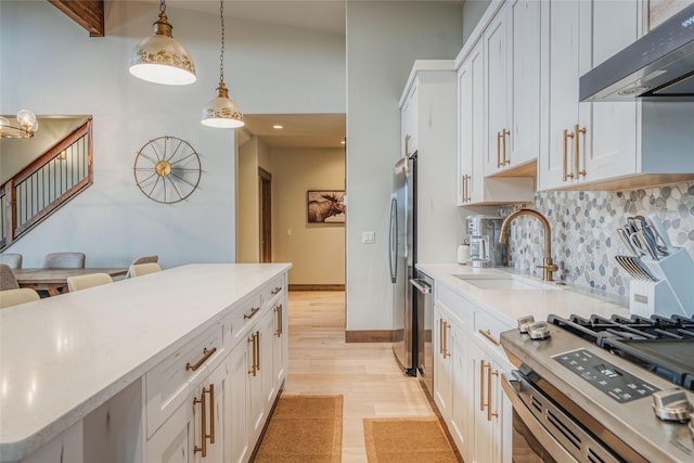 30 Ninebark Way, Eureka, MT 59917 - kitchen featuring a sink, decorative light fixtures, under cabinet range hood, backsplash, and white cabinets