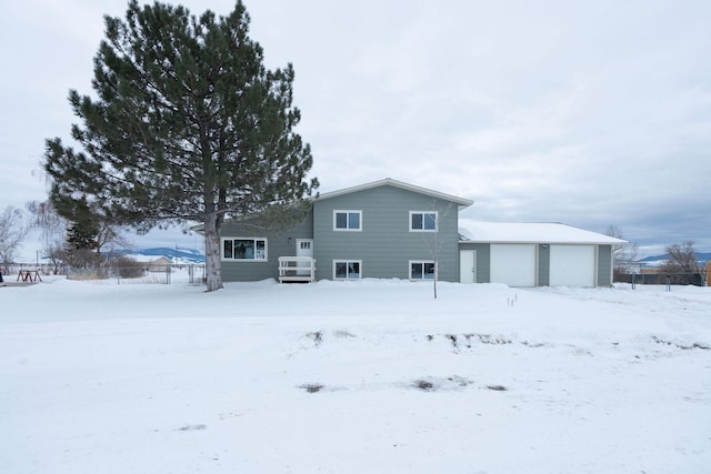 snow covered back of property featuring a garage