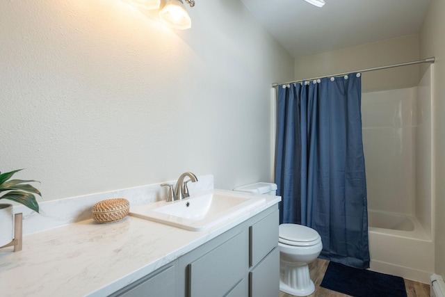 full bathroom with shower / bath combo, toilet, wood finished floors, baseboard heating, and vanity