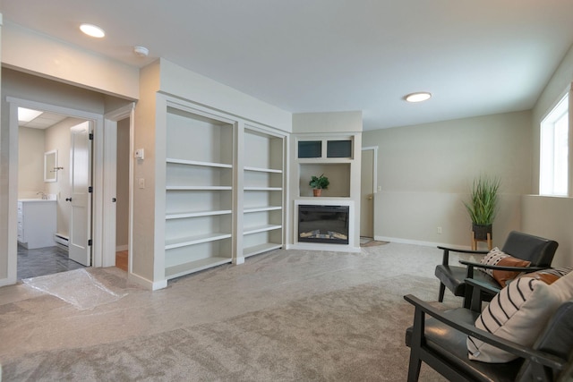 sitting room with built in features, a glass covered fireplace, carpet flooring, and baseboards