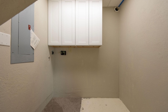 laundry room with a textured wall, cabinet space, and electric panel