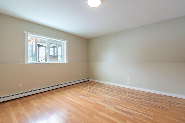 unfurnished room featuring light wood-style flooring, a baseboard heating unit, and baseboards