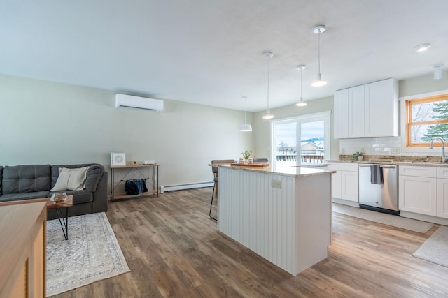 kitchen with stainless steel dishwasher, a wall mounted air conditioner, white cabinetry, and decorative light fixtures