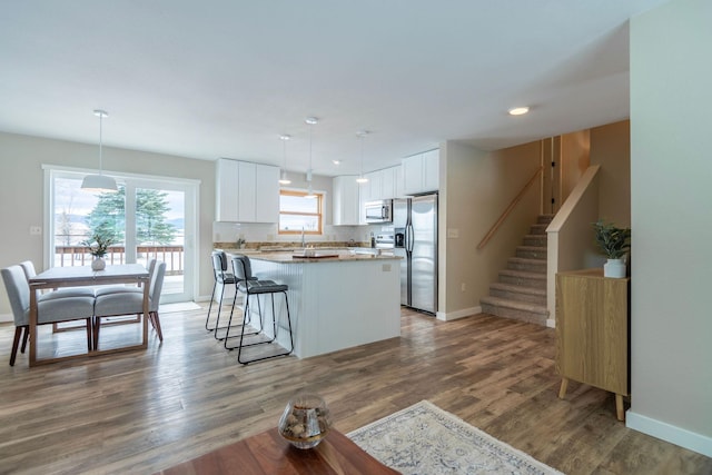 kitchen featuring stainless steel appliances, pendant lighting, white cabinetry, and a kitchen island