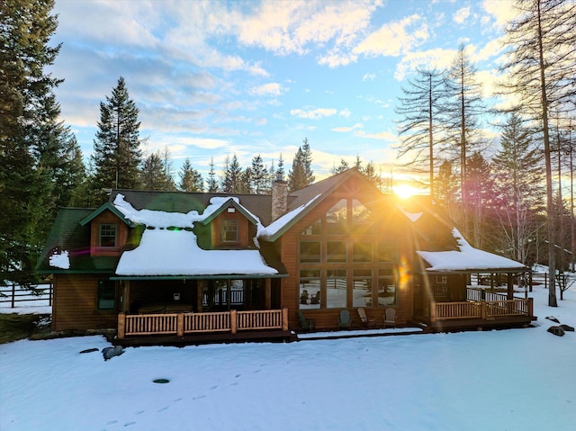 snow covered rear of property with a chimney