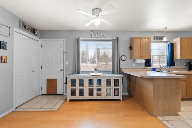 kitchen with a peninsula, glass insert cabinets, light countertops, and pendant lighting