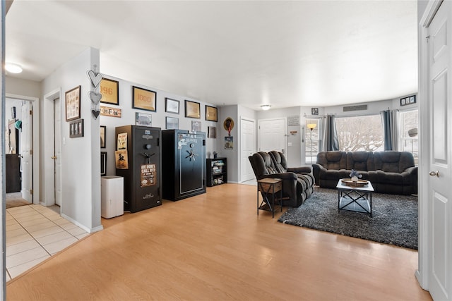 living room featuring visible vents, light wood-style flooring, and baseboards