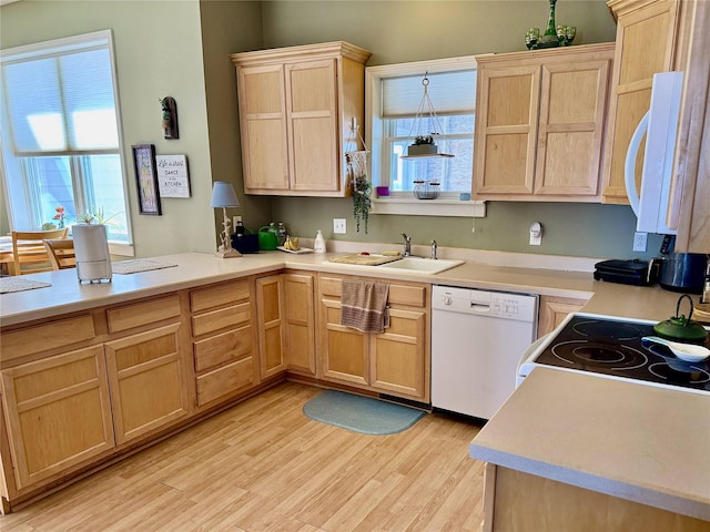 kitchen with light brown cabinets, white appliances, a sink, light countertops, and light wood finished floors