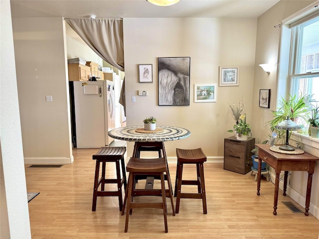 dining room with light wood-style floors, visible vents, and baseboards